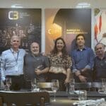 Imagem com homens e mulheres em frente a uma mesa de almoço e o texto diz: almoço do comitê executivo'.