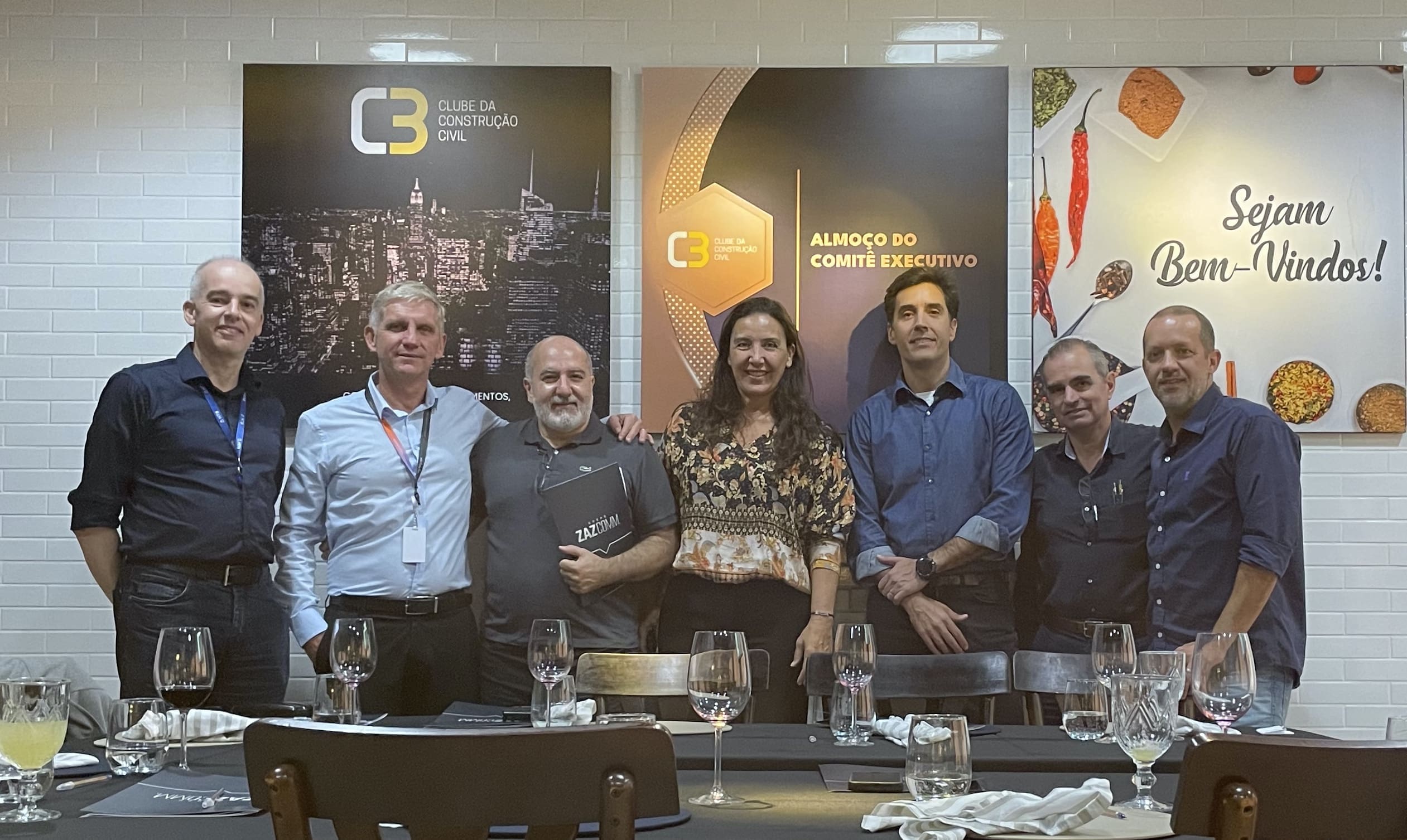 Imagem com homens e mulheres em frente a uma mesa de almoço e o texto diz: almoço do comitê executivo'.