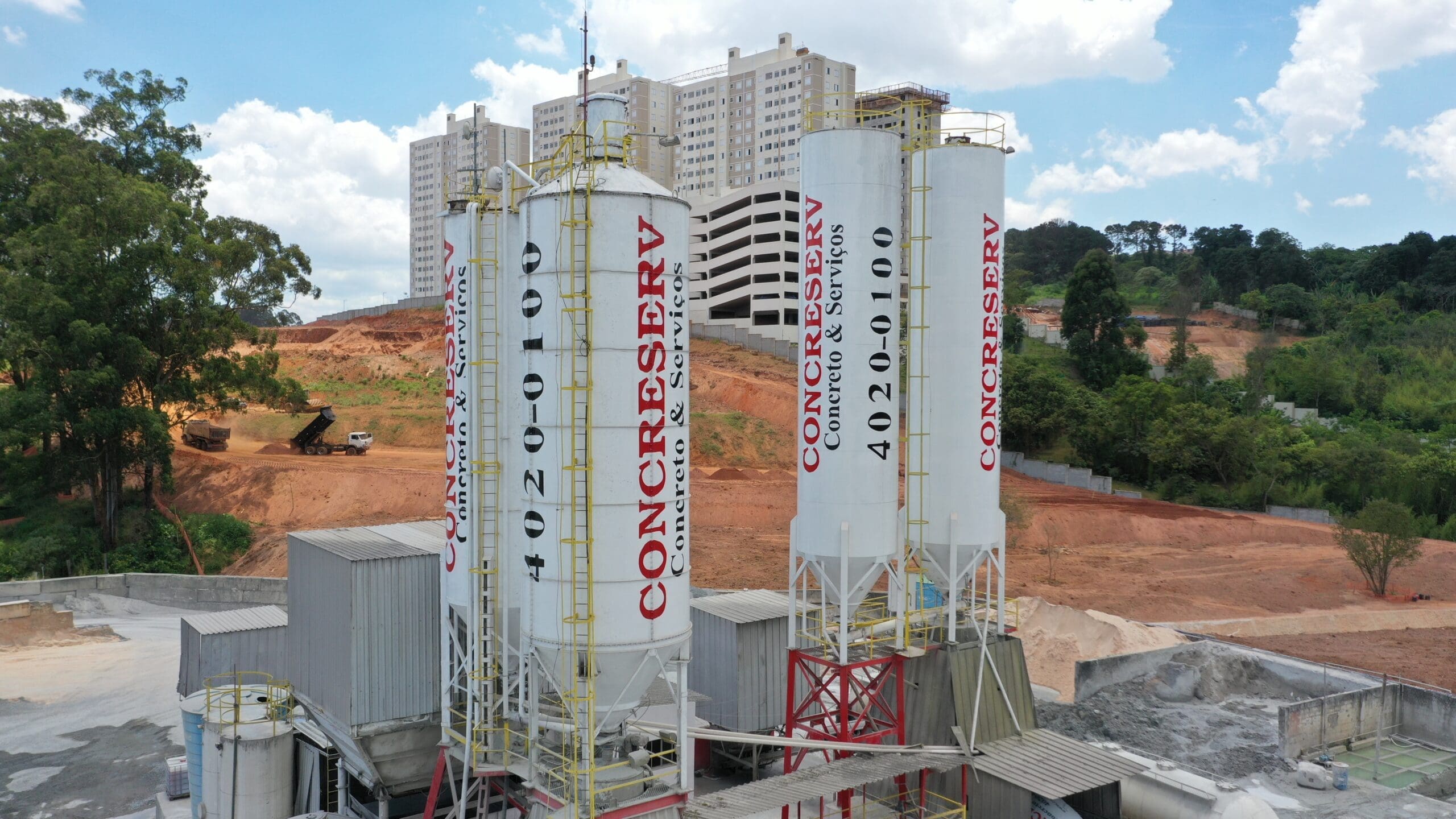 Imagem da concreteira Concreserv, vários cilíndos distribuídos pela imagem, com um fundo de terra e céu.