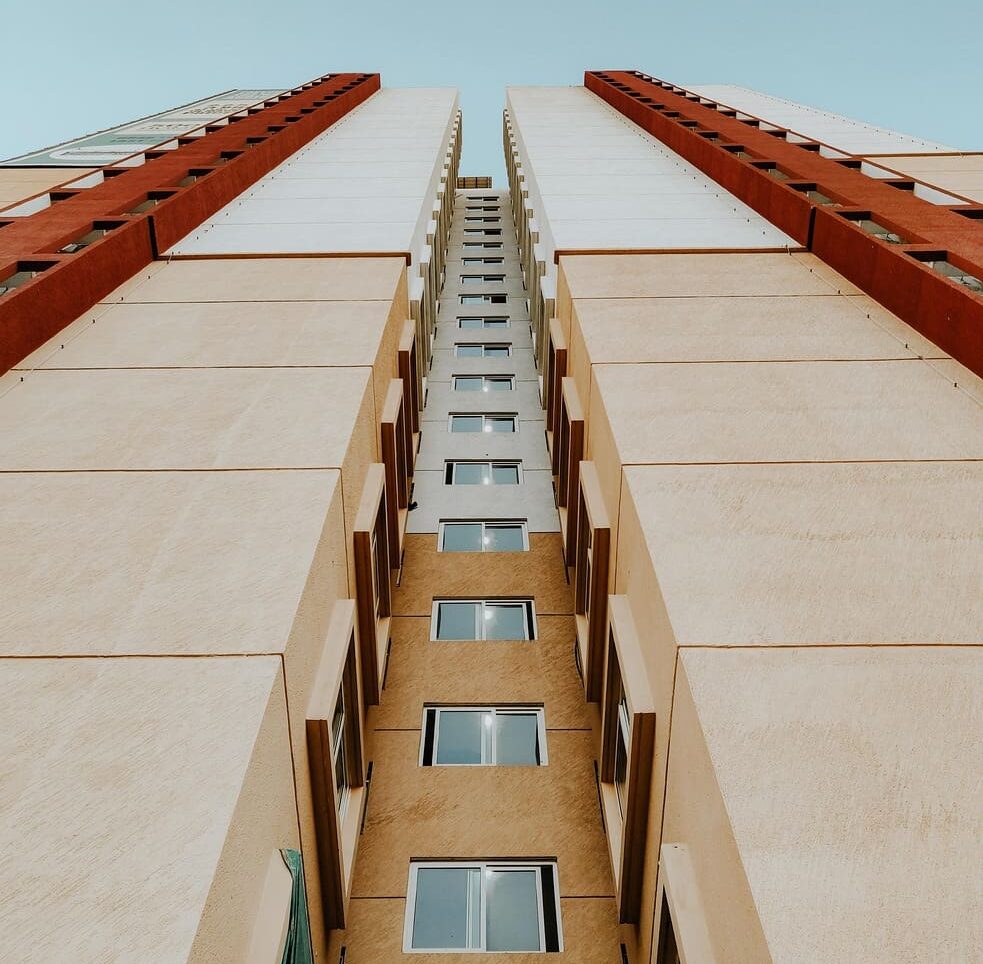 Edifício alto visto de baixo para cima, simbolizando fluxo contínuo, produtividade e eficiência na construção civil, conceito central do sistema lean para redução de prazos e aumento de resultados em obras.