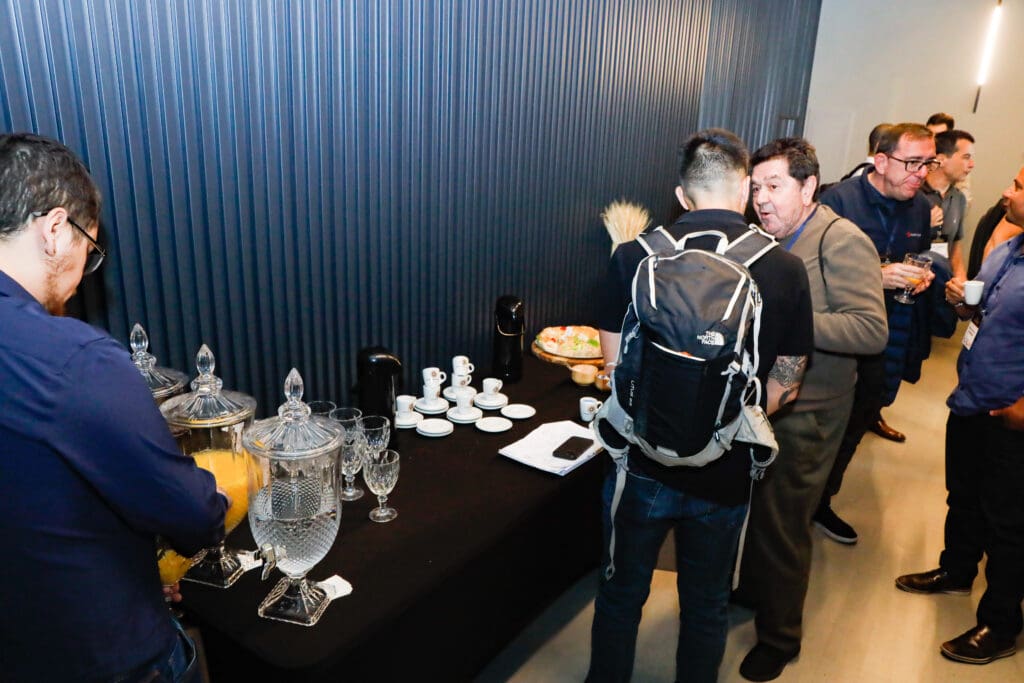 Participantes do evento Conexões do C3 aproveitam o coffee break para se servir e conversar, promovendo networking no setor da construção civil.