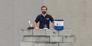 Representante da Ibratin com troféus de premiação, blocos sustentáveis e embalagem da Textura Biotex, simbolizando inovação e economia circular no setor de tintas.
