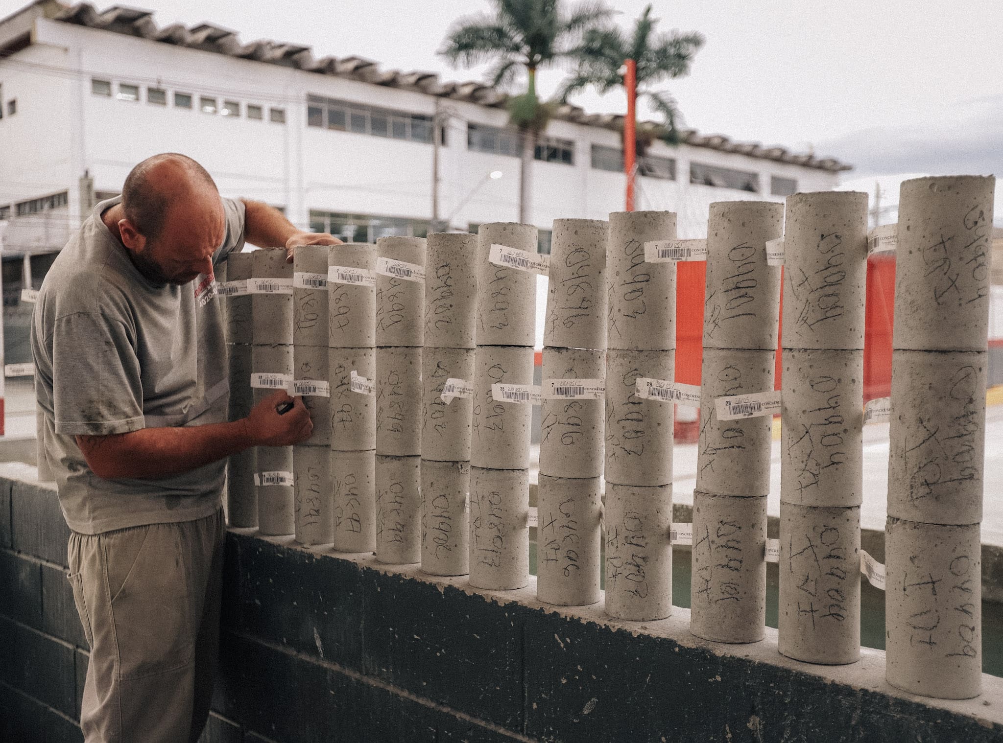 Técnico da Concreserv identificando corpos de prova cilíndricos de concreto com etiquetas e anotações, processo essencial para rastreabilidade e controle de qualidade do material.