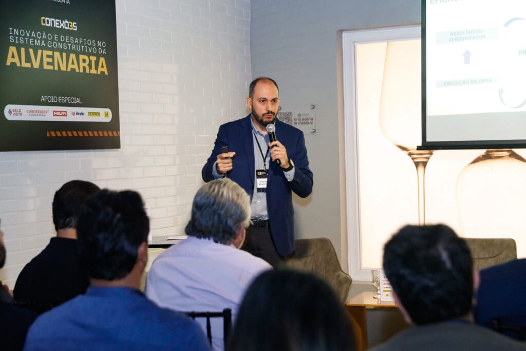 André Wendler apresenta conceitos de eficiência e resultados em projetos de alvenaria durante o Conexões C3, diante de uma plateia atenta.