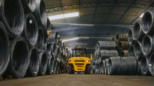 Empilhadeira movimentando bobinas de aço em galpão industrial da Udiaço, referência em corte e dobra industrializado.
