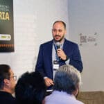André Wendler apresenta palestra sobre projeto colaborativo em alvenaria durante o evento Conexões C3, diante de uma plateia atenta.