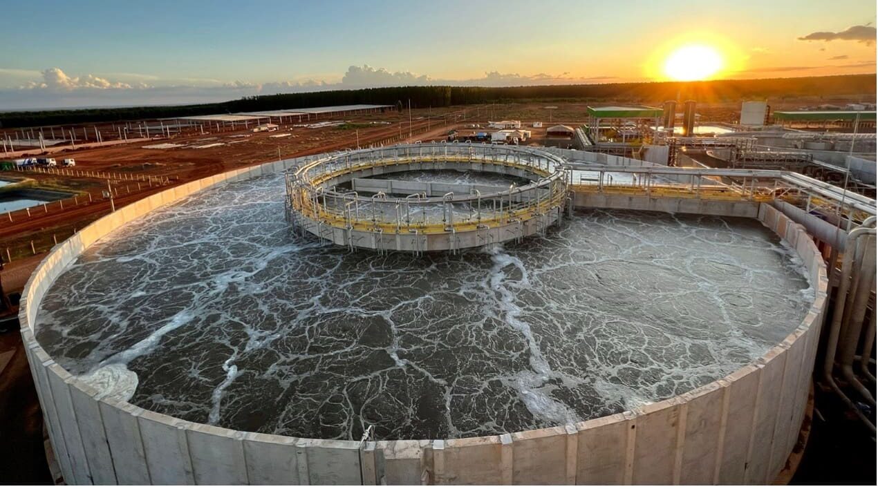 Tanque circular de tratamento de efluentes industriais ao entardecer, destacando a importância da proteção antimicrobiana no saneamento.