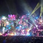 Palco principal do Tomorrowland Brasil 2025 em Itu iluminado à noite, com projeções coloridas, efeitos de luz e uma multidão de pessoas.