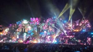 Palco principal do Tomorrowland Brasil 2025 em Itu iluminado à noite, com projeções coloridas, efeitos de luz e uma multidão de pessoas.