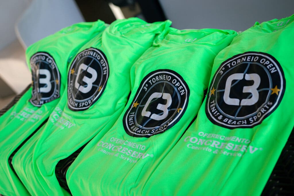Camisetas verdes do Kit Atleta do 3º C3 Open Beach Sports, com logotipo do evento e patrocínio da Concreserv, organizadas para distribuição aos competidores.