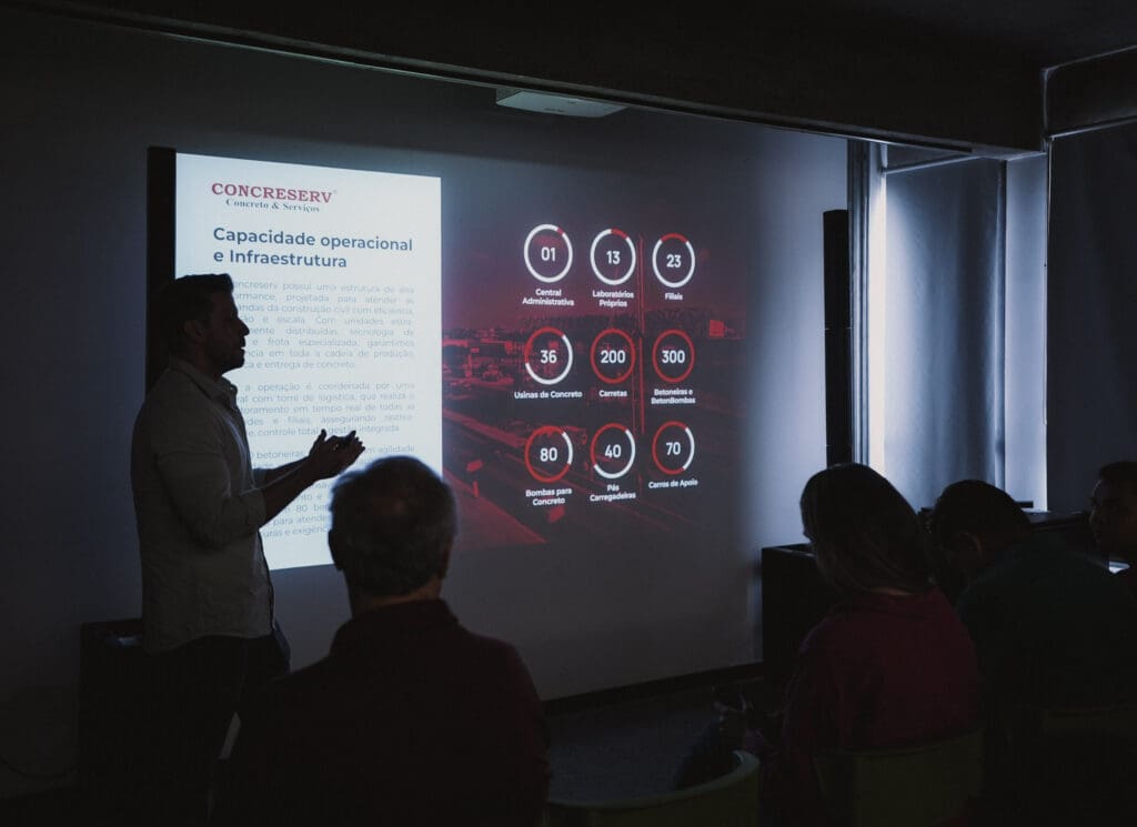 Palestrante apresenta dados de capacidade operacional e infraestrutura da Concreserv em projeção para plateia durante evento técnico.