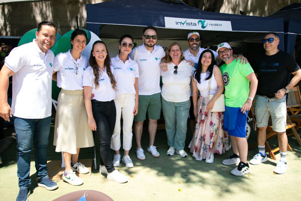 Equipe e visitantes posam sorridentes em frente ao stand do inVista no Bem durante o 3º C3 Open Beach Sports, promovendo ações sociais e integração no evento.