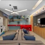 Espaço moderno de lavanderia compartilhada OMO em condomínio residencial, com máquinas de lavar e secar, área de estar com sofás, televisão e ambiente decorado, funcionando 24 horas.