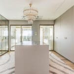 Walk-in closet sofisticado com armários espelhados, ilha central e iluminação elegante, integrado ao banheiro.