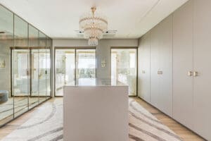Walk-in closet sofisticado com armários espelhados, ilha central e iluminação elegante, integrado ao banheiro.