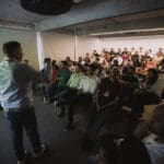 Palestrante conduzindo apresentação para um auditório cheio durante encontro técnico da Concreserv sobre inovação e sustentabilidade no concreto.
