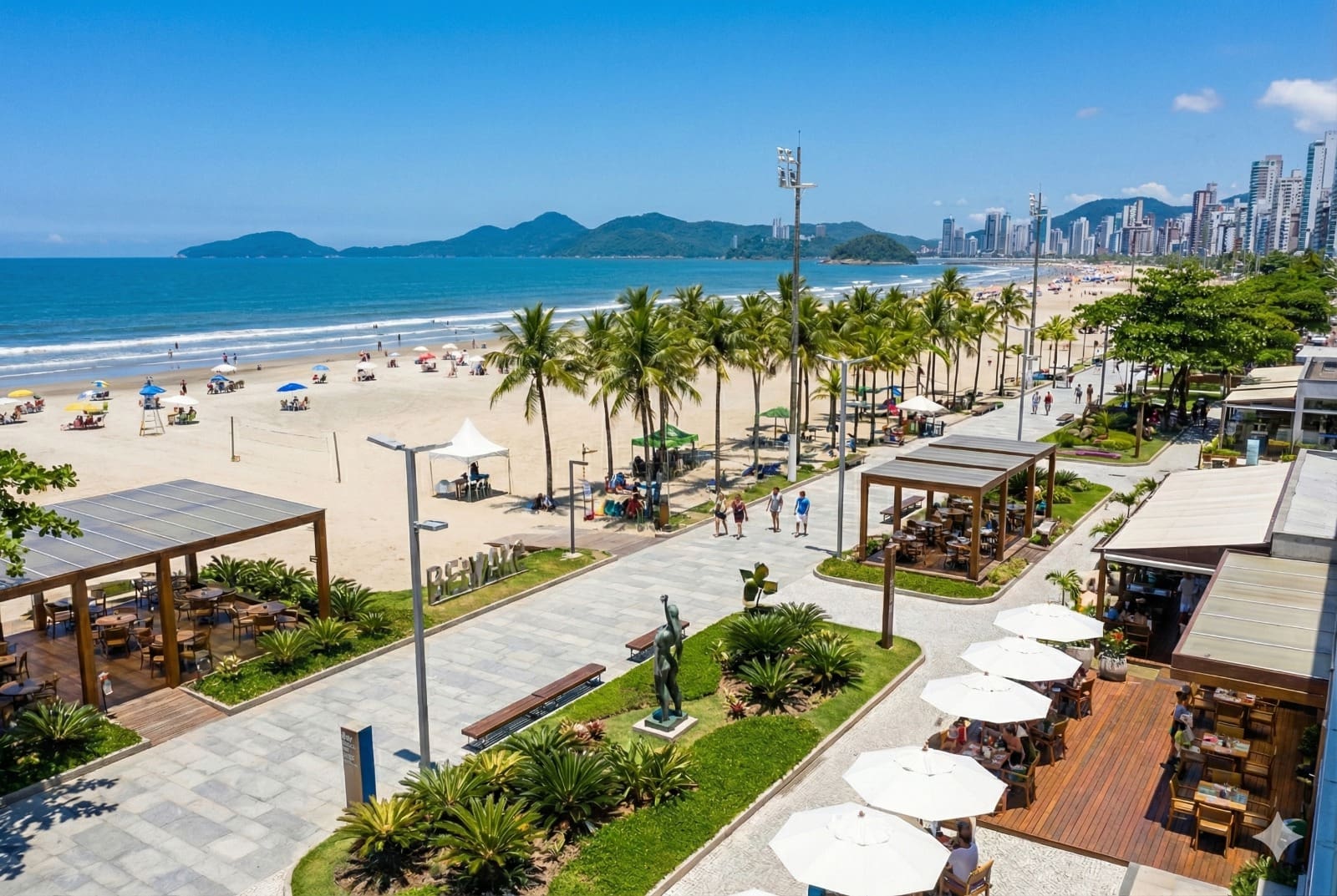 Vista aérea de uma orla revitalizada em Balneário Camboriú, Santa Catarina, mostrando calçadão moderno com quiosques, ciclovia, palmeiras, áreas de lazer e a praia ao fundo, com o mar azul e prédios altos na linha do horizonte.