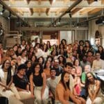 Grupo diverso de jovens estudantes e profissionais reunidos em ambiente moderno durante evento do Programa Aproxima, que promove diversidade e inclusão étnico-racial na arquitetura.