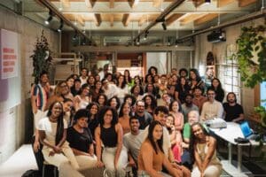 Grupo diverso de jovens estudantes e profissionais reunidos em ambiente moderno durante evento do Programa Aproxima, que promove diversidade e inclusão étnico-racial na arquitetura.