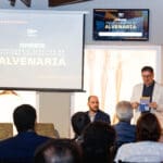 Alexandre Britez mediando painel sobre inovação e desafios no sistema construtivo da alvenaria durante o evento Conexões C3, diante de uma plateia atenta.