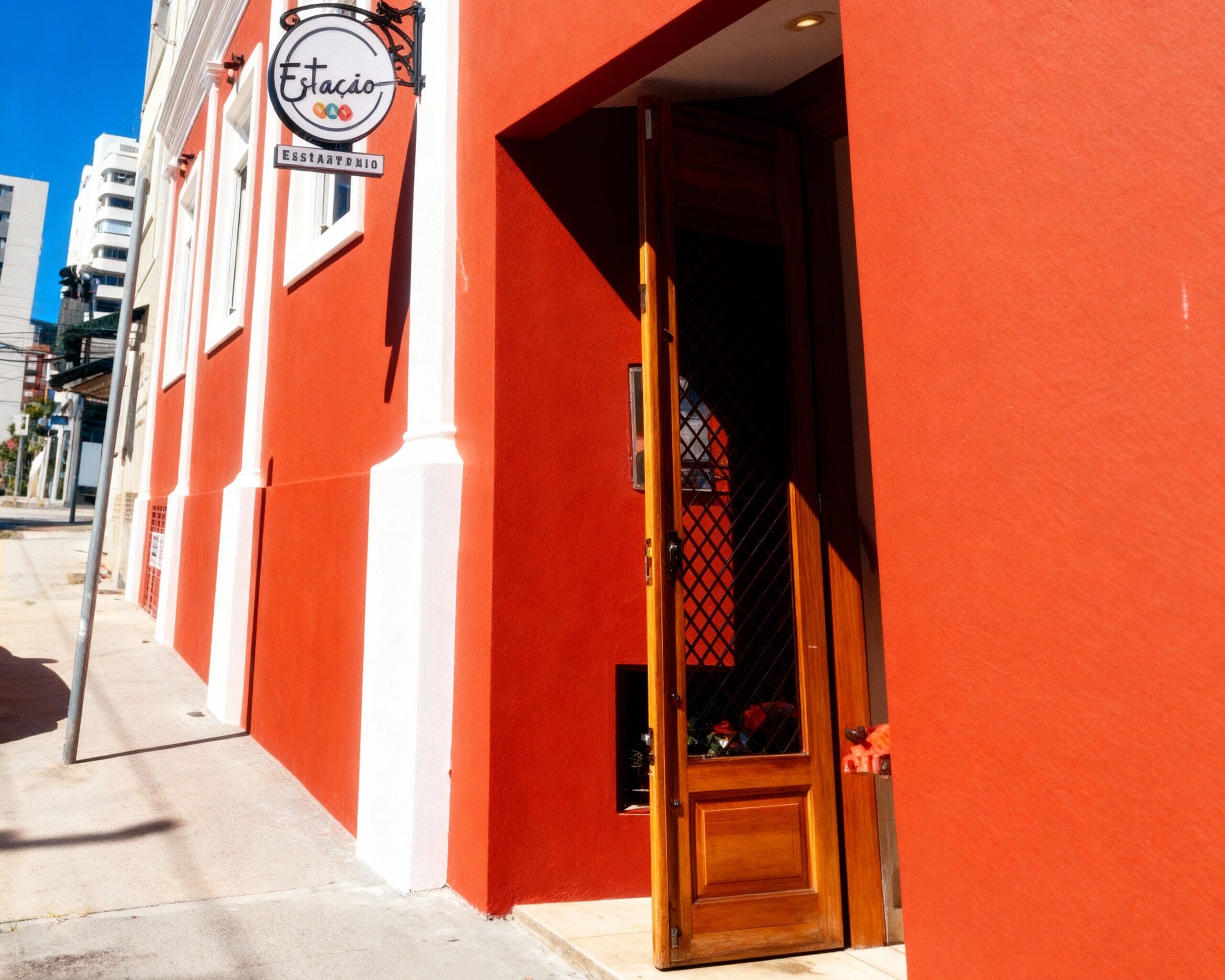 Fachada restaurada de um edifício histórico com pintura vermelha e detalhes brancos, abrigando um restaurante, em área urbana revitalizada.