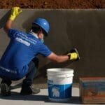 Técnico aplicando sistema de impermeabilização em piscina durante obra, garantindo proteção contra infiltrações.