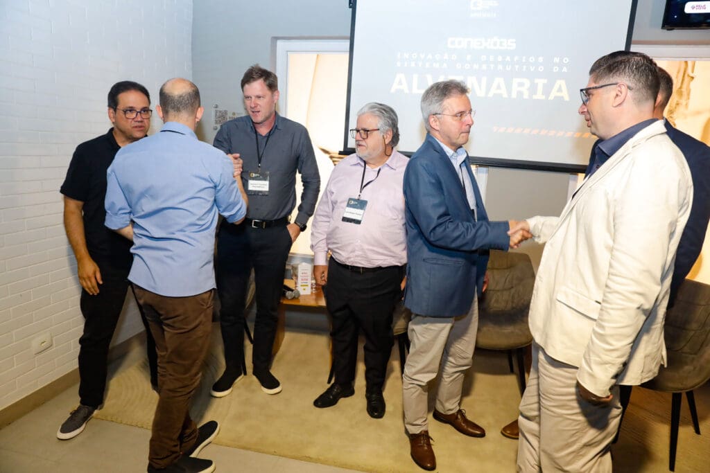 Alexandre Britez cumprimenta o painelista Dr. Ubiraci Souza, ao lado dos painelistas André Wendler, Prof. Luiz Sérgio Franco e Gustavo Trombeli, além do palestrante David Fratel e do presidente do C3, Rodolfo Zagallo, durante o evento Conexões C3 sobre inovação na alvenaria estrutural.