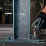 Engenheiro ajustando fixador estrutural com luva de proteção em base metálica, representando integração entre projeto e execução com soluções SPEC2SITE Hilti.
