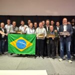 Equipe brasileira da Concreserv e parceiros celebram premiação internacional no Golden Trowel Awards 2025, em Las Vegas, segurando troféus e a bandeira do Brasil.