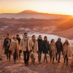 Grupo de profissionais da construção civil caminha pelo deserto do Atacama durante o pôr do sol, simbolizando conexões e networking no setor.