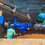 Dois colaboradores da Concrejato Engenharia instalam válvula de grande porte em rede de abastecimento de água, em obra de saneamento básico no Brasil
