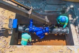 Dois colaboradores da Concrejato Engenharia instalam válvula de grande porte em rede de abastecimento de água, em obra de saneamento básico no Brasil
