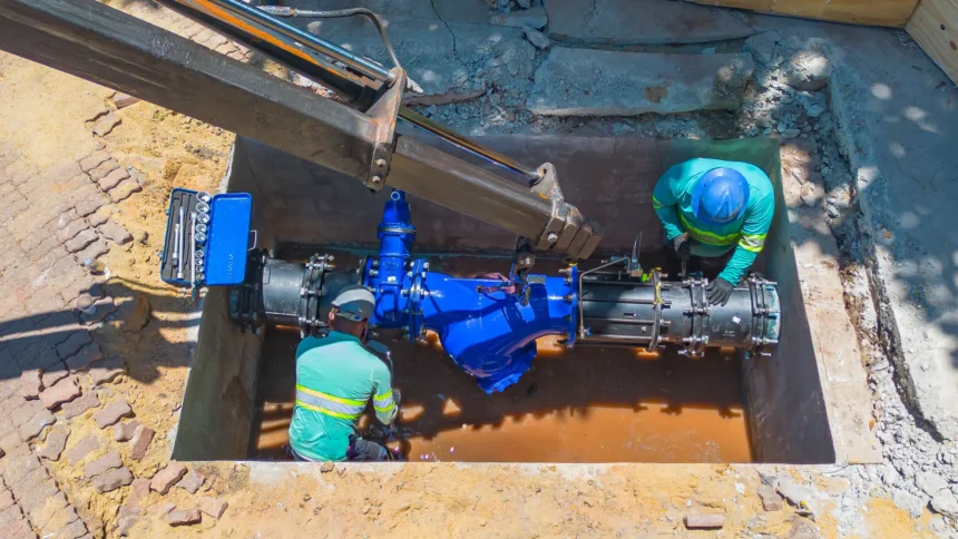 Dois colaboradores da Concrejato Engenharia instalam válvula de grande porte em rede de abastecimento de água, em obra de saneamento básico no Brasil