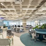 Escritório corporativo moderno entregue via Turnkey pela Space, com áreas colaborativas, estações de trabalho abertas, vegetação e teto de concreto aparente