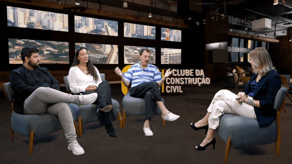 Três gerações da família Bigucci e a apresentadora Lucedile Antunes participam de um bate-papo sobre sucessão familiar e inovação na construção civil, sentados em um estúdio moderno com o letreiro “Clube da Construção Civil” ao fundo.