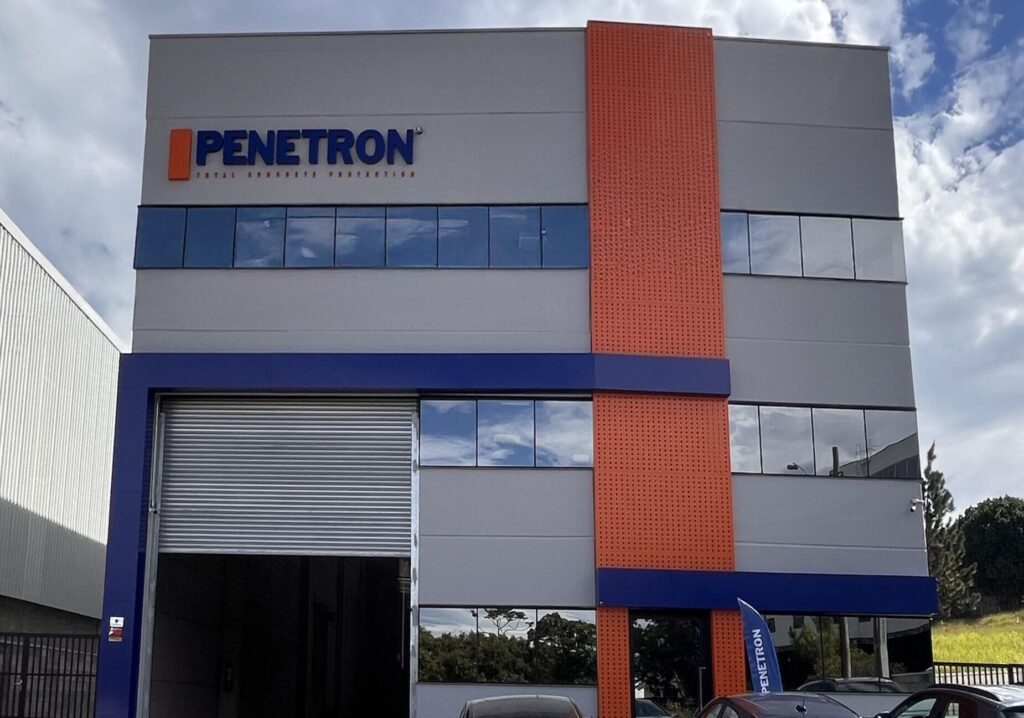 Fachada do Centro de Treinamentos Penetron Brasil em Arujá (SP), com logo da empresa em destaque e estacionamento à frente.