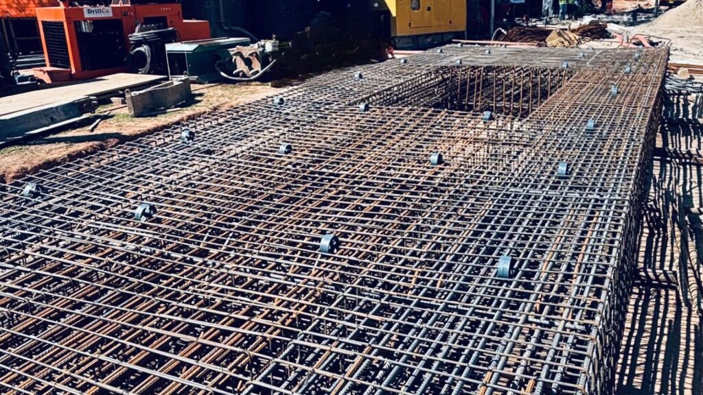 Estrutura de armação de aço reticulada para fundação, evidenciando a complexidade e precisão do trabalho realizado pela Servter SP em um canteiro de obras.