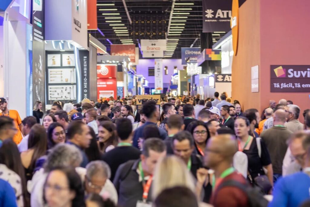 Corredor lotado de visitantes circulando entre estandes de grandes marcas durante a FEICON 2026, evidenciando o alto engajamento do público no evento.