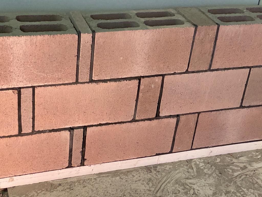 Detalhe de parede construída com blocos cerâmicos estruturais, evidenciando o alinhamento e a disposição dos blocos.