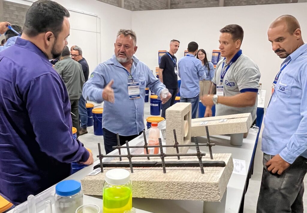 Profissionais da construção civil analisam amostras e discutem soluções Penetron para impermeabilização de concreto durante treinamento prático em Arujá (SP).