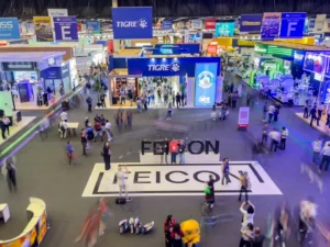 Vista panorâmica do pavilhão principal da FEICON 2026, com grande movimentação de visitantes e estandes de marcas líderes do setor da construção civil.