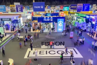 Vista panorâmica do pavilhão principal da FEICON 2026, com grande movimentação de visitantes e estandes de marcas líderes do setor da construção civil.