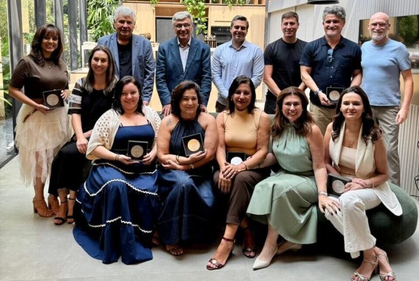 Equipe da SCA Jardim Europa posa com diretores e colaboradores premiados, exibindo troféus de Revenda Diamante, Melhor Gerente e Consultores Tops em ambiente moderno e iluminado.