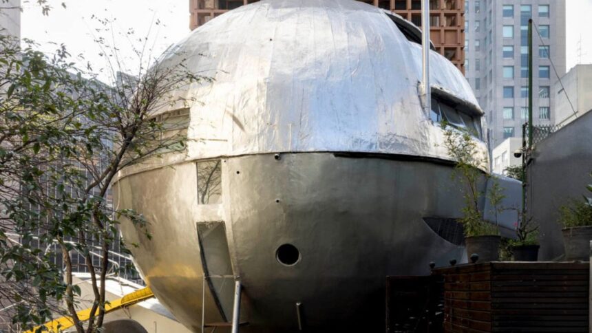 Vista frontal da Casa Bola, estrutura arquitetônica esférica e metálica projetada por Eduardo Longo, destacando-se entre edifícios no Jardim Paulistano, São Paulo.