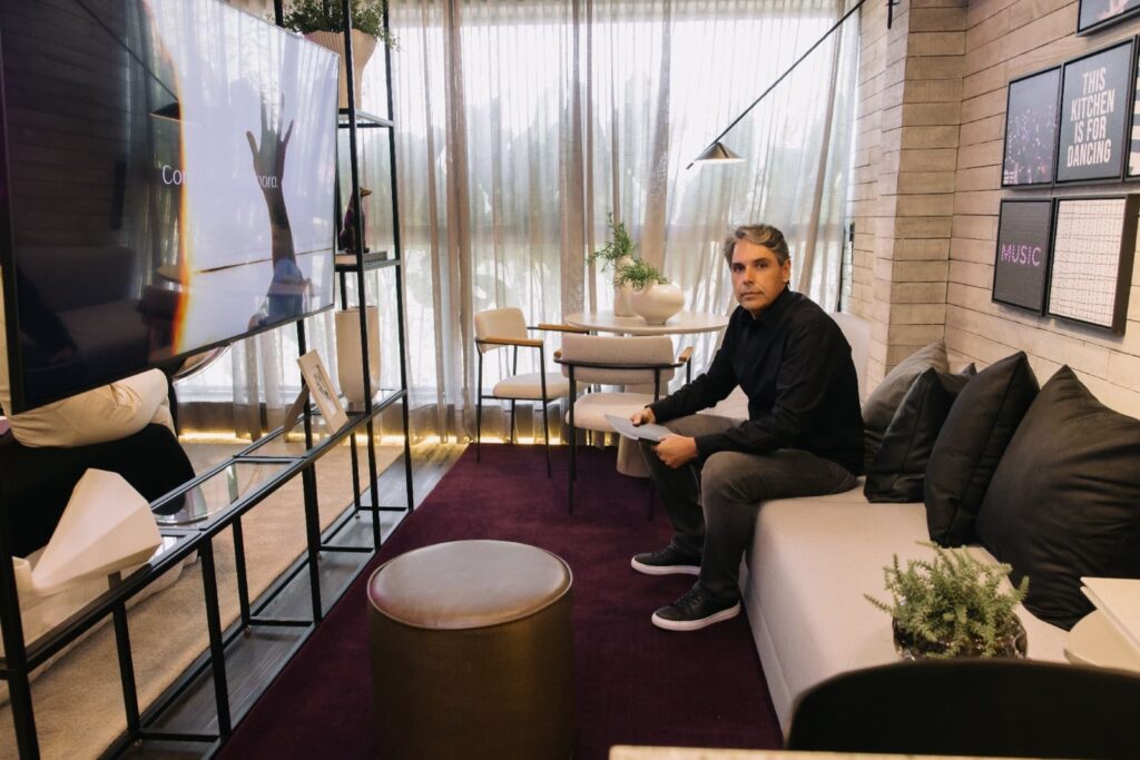 Luis Café, arquiteto responsável pela LCVC Arquitetura e Interiores, sentado em ambiente de living moderno e sofisticado, com decoração contemporânea e iluminação natural.
