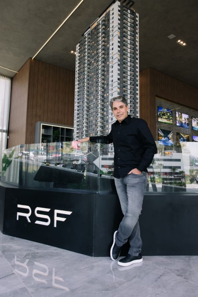 Luis Café, arquiteto da LCVC Arquitetura e Interiores, ao lado de uma maquete de edifício residencial de alto padrão no showroom da RSF, simbolizando inovação e excelência em projetos imobiliários em Alphaville.