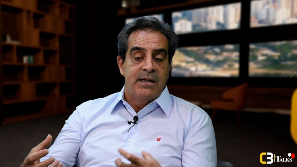 Mario Rocha, CEO da Rocontec, fala durante entrevista no C3 Talks, vestindo camisa clara e microfone de lapela, com ambiente corporativo ao fundo.