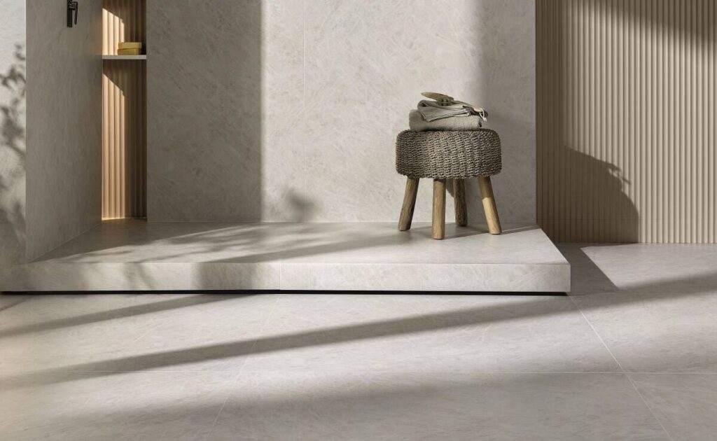 Ambiente iluminado com revestimento Cristallo da Portobello, destacando piso e parede em tons claros, textura sofisticada e banco de fibras naturais.