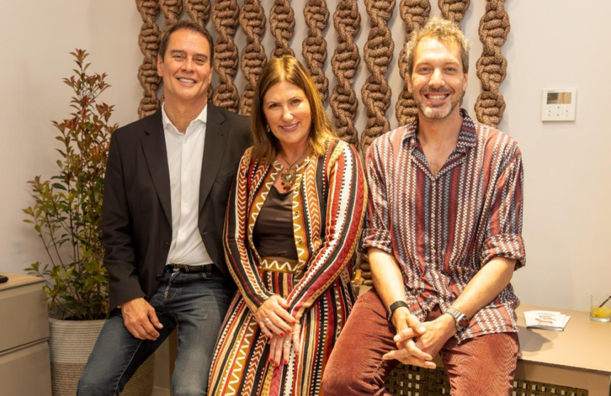 Marcello Anthony, Tatiana Mandelli e Francesco Maccapani Missoni sorrindo juntos durante a abertura da loja Tidelli em Lisboa, sentados em frente a um painel de cordas artesanais.