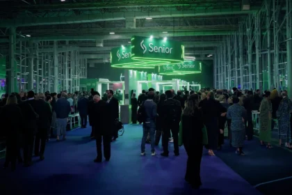 Público circulando e interagindo no Pavilhão C do Transamérica Expo Center durante o Senior Experience 2026, com destaque para o estande iluminado da Senior Sistemas ao fundo.